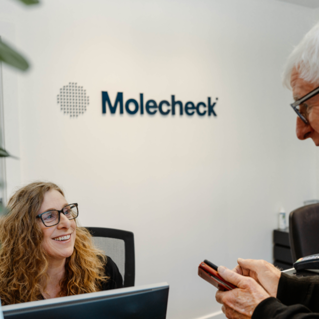 A molecheck receptionist talking to a happy patient